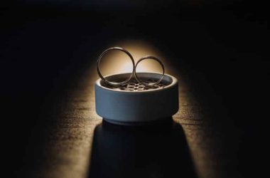 two gold wedding rings in a white box on a black background.